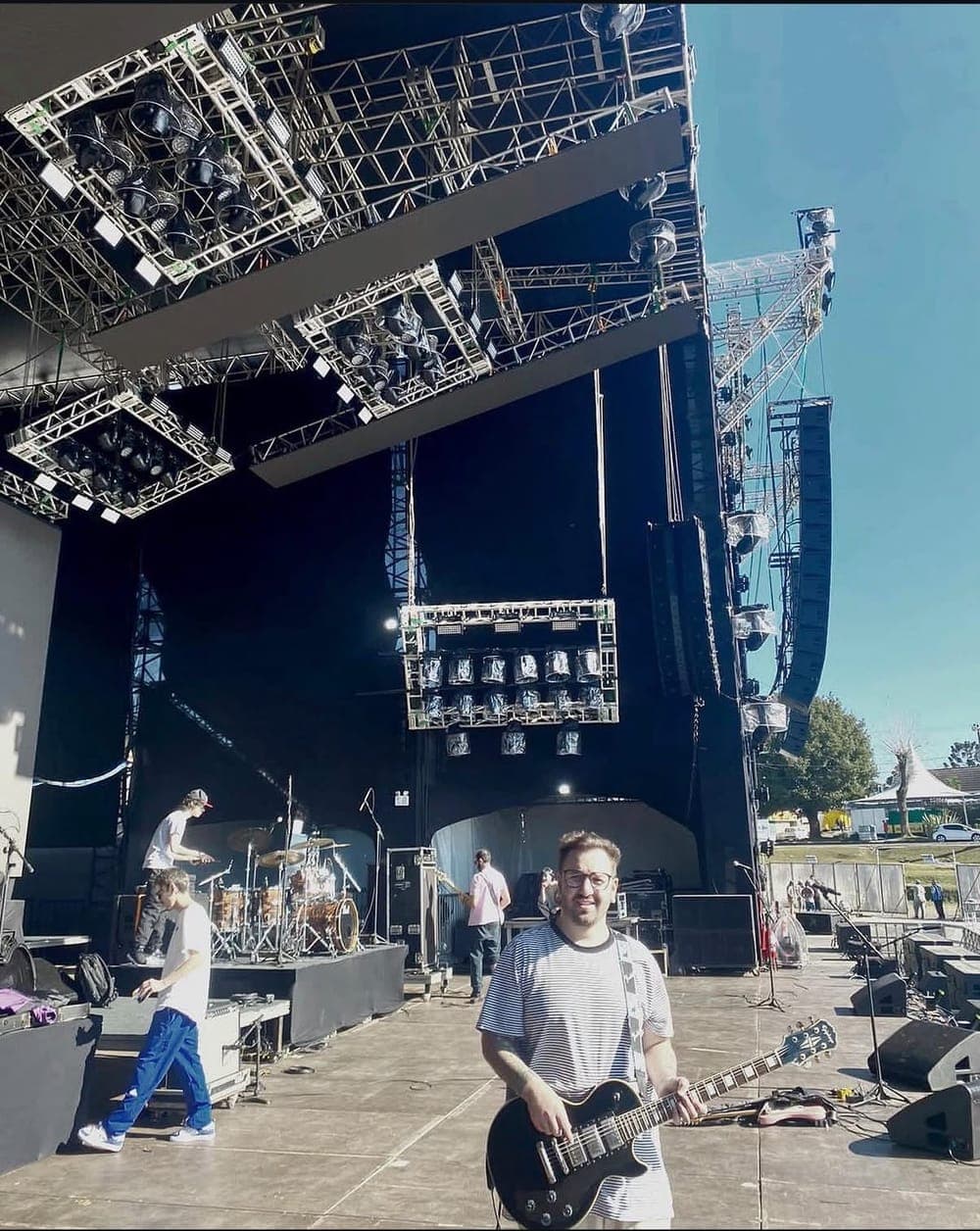 Mateus Rosa com a guitarra em um grande palco durante o dia